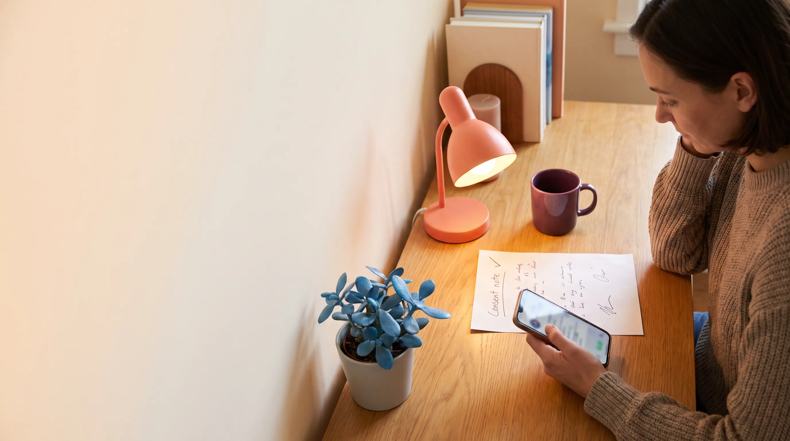 Adult reviewing a phone and a consent note at a calm desk